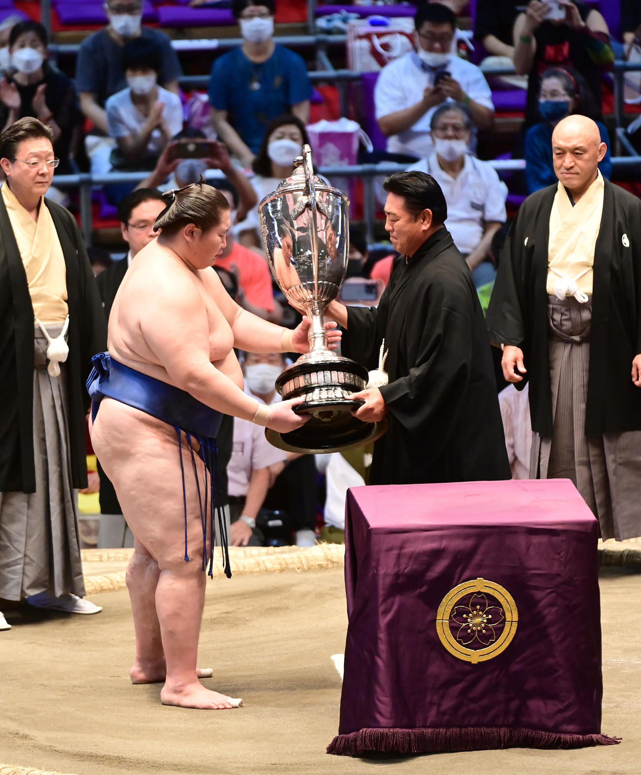 初優勝を飾った逸ノ城（左）は新型コロナウイルス感染者が出たため休場となった八角理事長の代理を務めた陸奥事業部長から賜杯贈呈を受ける。左奥は伊勢ケ浜審判部長、右奥は粂川審判部副部長（撮影・小沢裕）