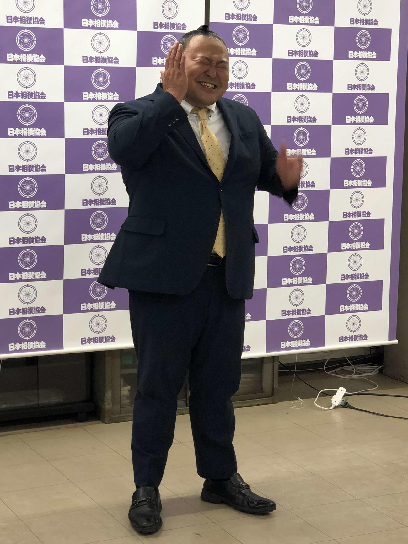 12月3日の断髪式開催を発表する桐山親方は、緊張でこわばった表情を自分でたたいてほぐす