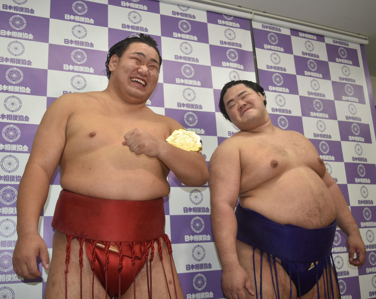 全日本力士選士権で初優勝して選士権章を腕に巻いて笑顔を見せる豊昇龍。右はうらやましそうに見る明生
