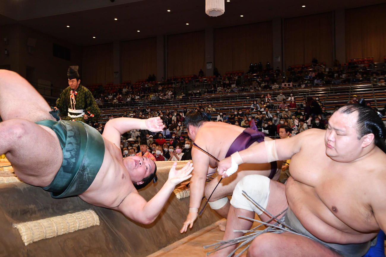 遠藤（中央）を寄り切りで破った錦木は勢い余って土俵下に落ちる。右は北勝富士（撮影・岩下翔太）