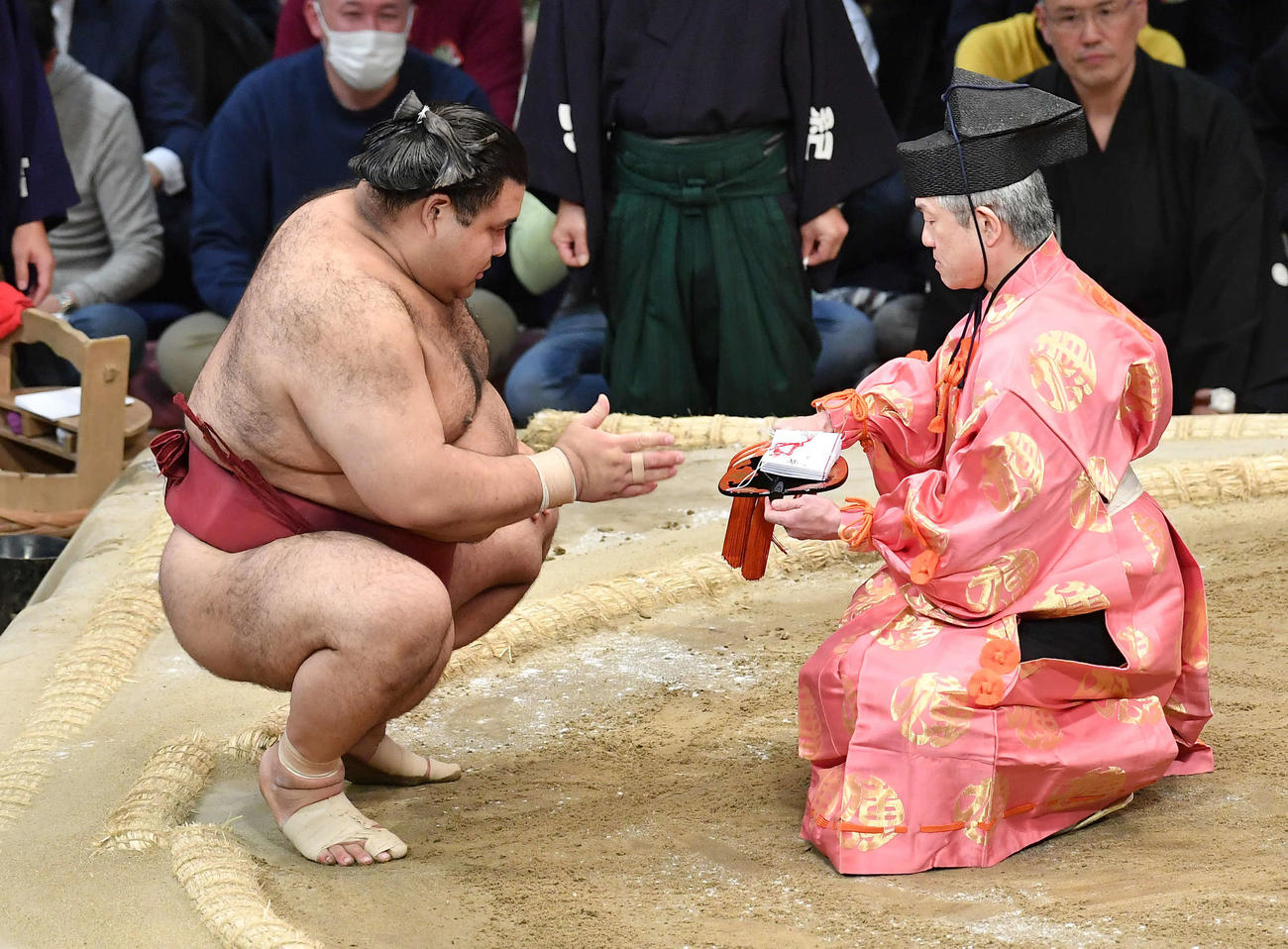 輝をはたき込みで破り、懸賞金を受け取る高安（撮影・岩下翔太）