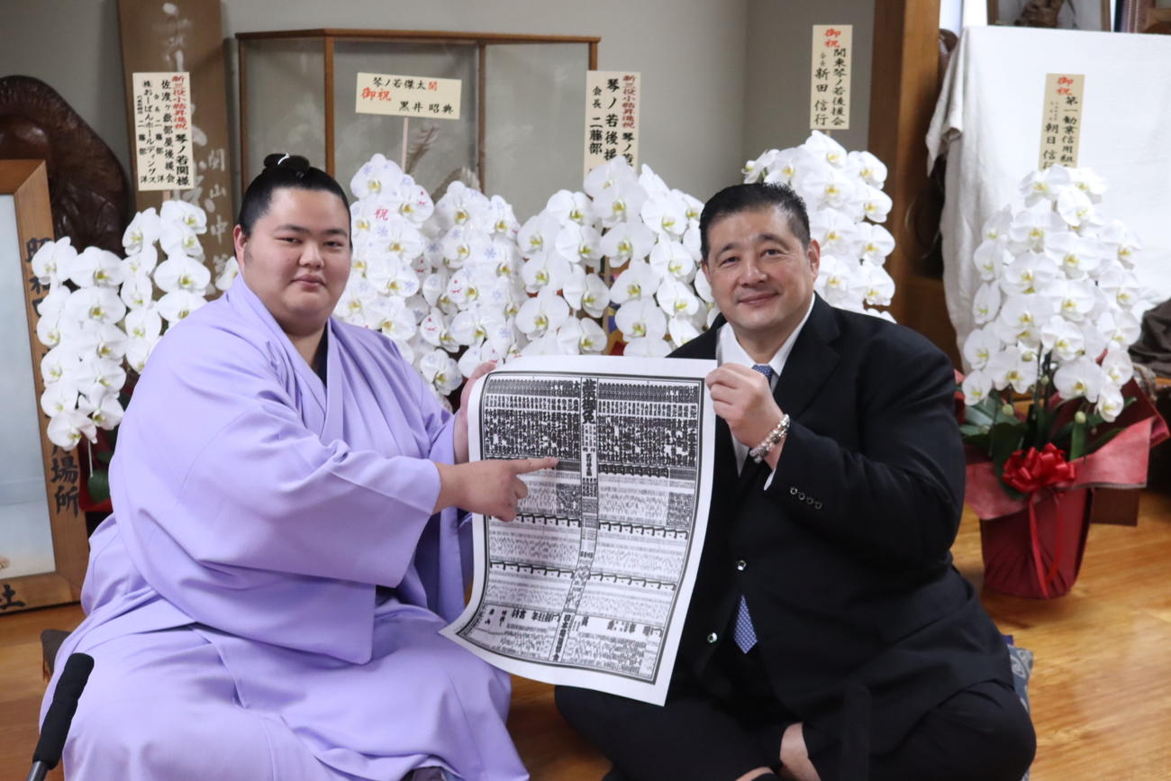 新三役の琴ノ若（左）は、新番付の自身のしこ名を指さし、父で師匠の佐渡ケ嶽親方とともに笑顔を見せた（日本相撲協会提供）