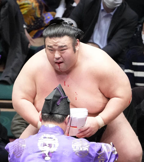 口からの流血に険しい表情を見せながら懸賞金を手にする貴景勝（撮影・小沢裕）