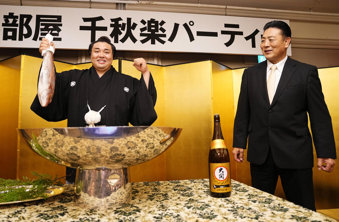 幕内初優勝を決めた霧馬山は祝勝会会場でお祝いの鯛を手に笑顔でガッツポーズ。右は陸奥親方
