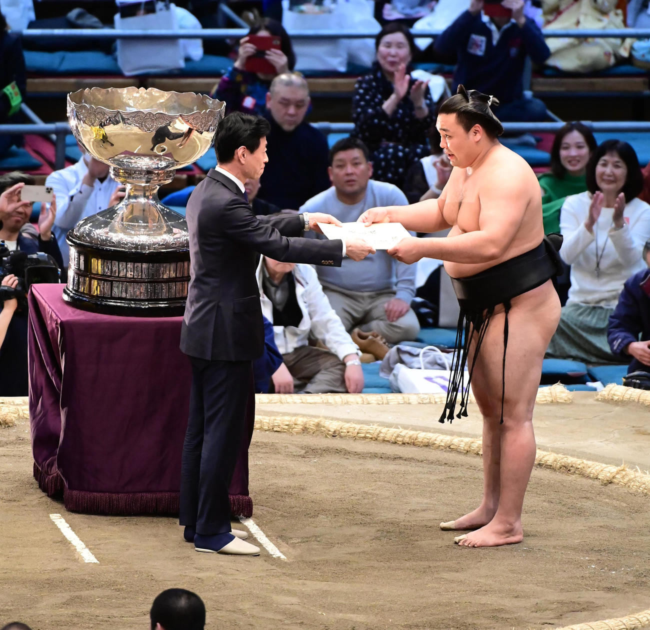 幕内初優勝を決めた霧馬山は内閣総理大臣杯授与に訪れた西村経産相（左）から表彰状を受け取る（撮影・小沢裕）