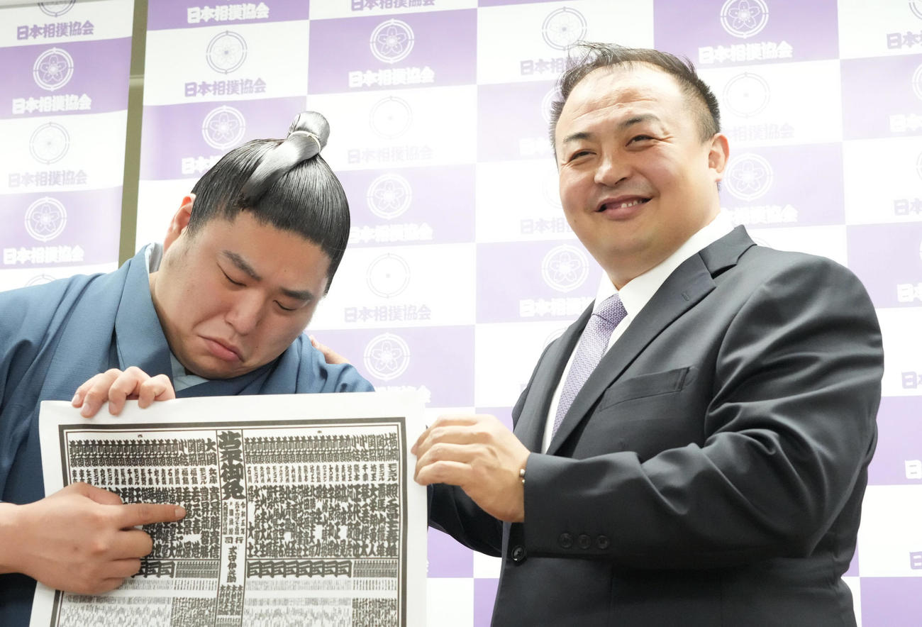 大相撲夏場所の番付発表会見で自らのしこ名の位置を確認しながら指さす若元春。右は師匠の荒汐親方（撮影・小沢裕）