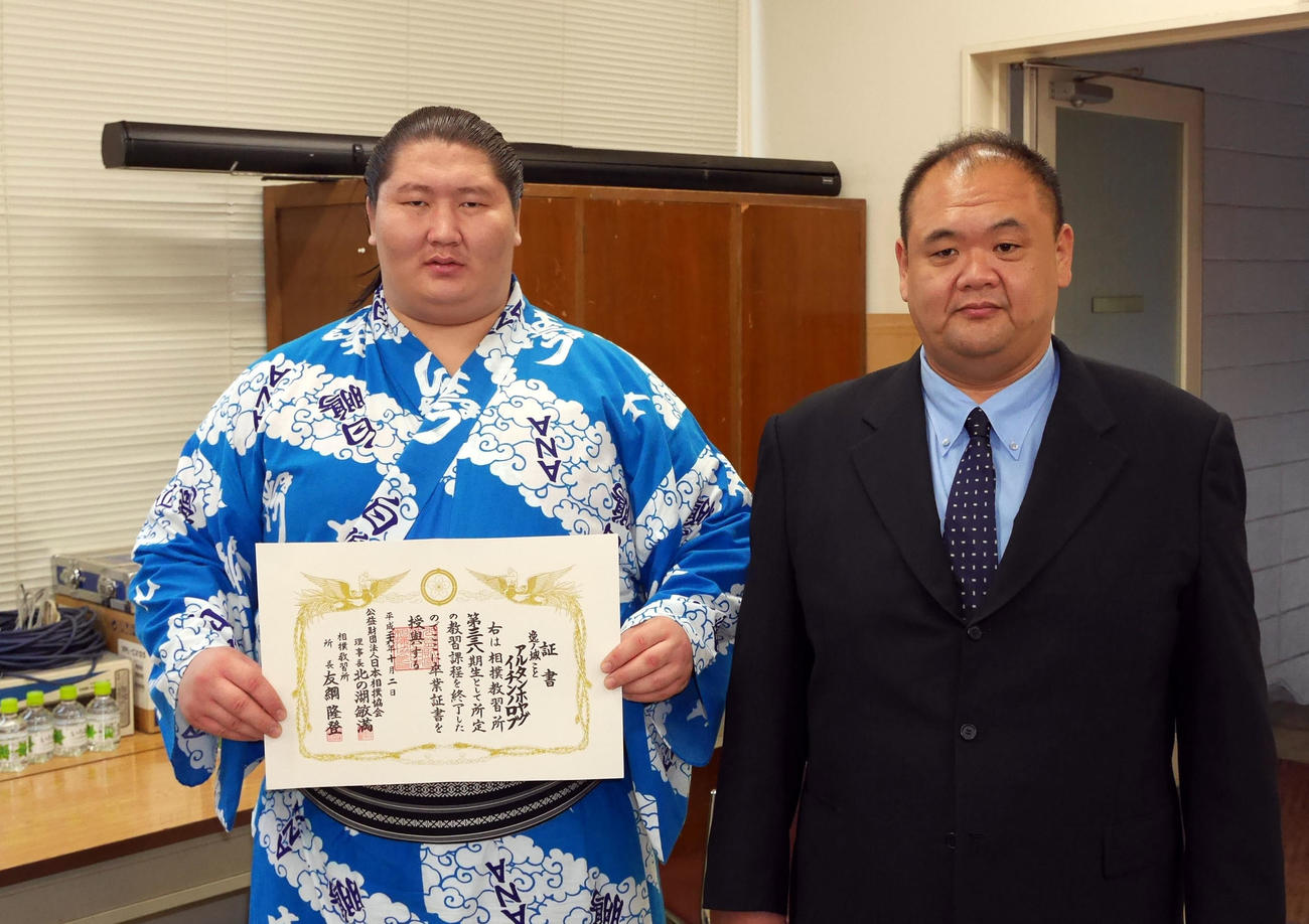 相撲教習所卒業式で、卒業証書を手にする逸ノ城（左）。右は師匠の湊親方（元前頭湊富士）（2014年10月2日撮影）