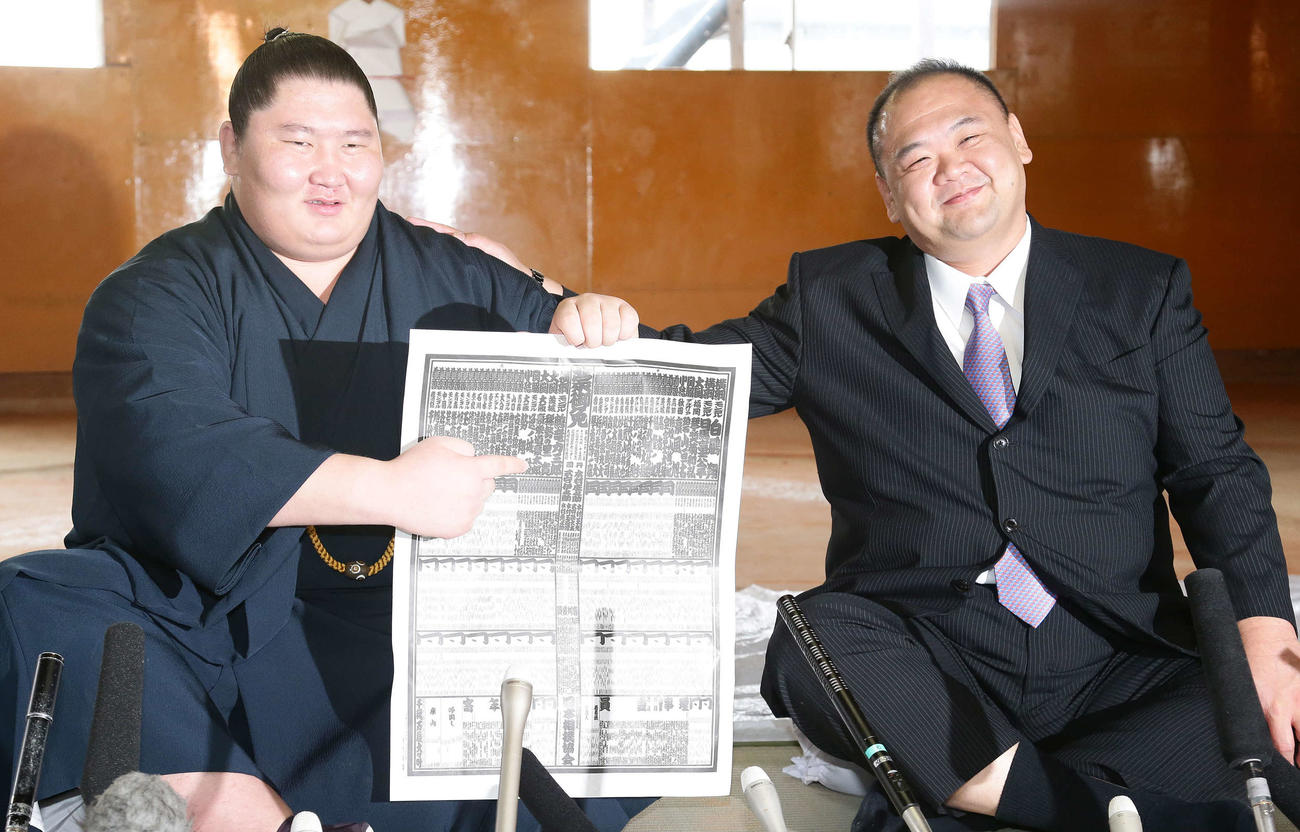 入幕2場所で関脇となり番付表の自身の名前を指さす逸ノ城（左）。右は師匠の湊親方（2014年10月27日撮影）