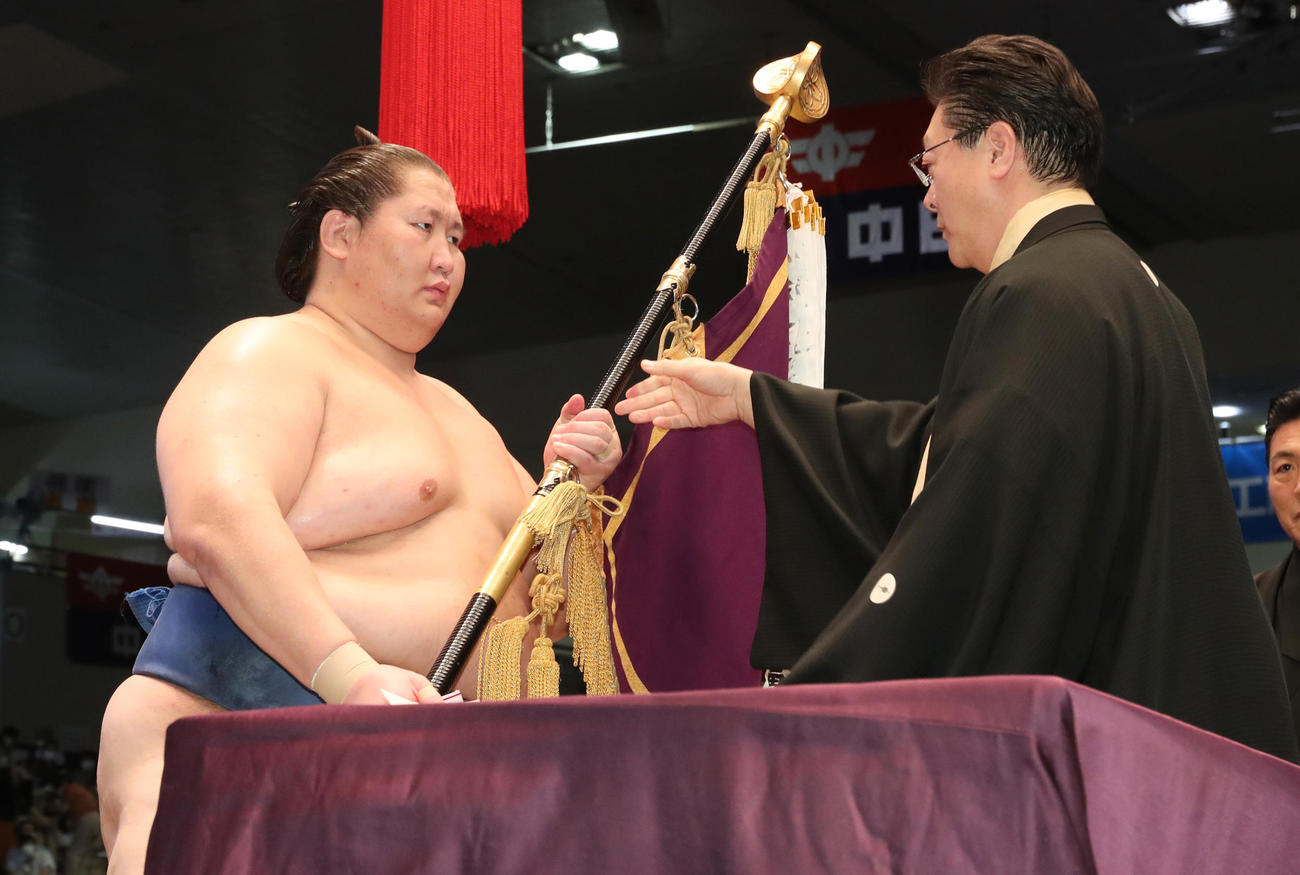 2022年7月24日、表彰式で伊勢ケ浜審判部長（右）から優勝旗を受け取る逸ノ城