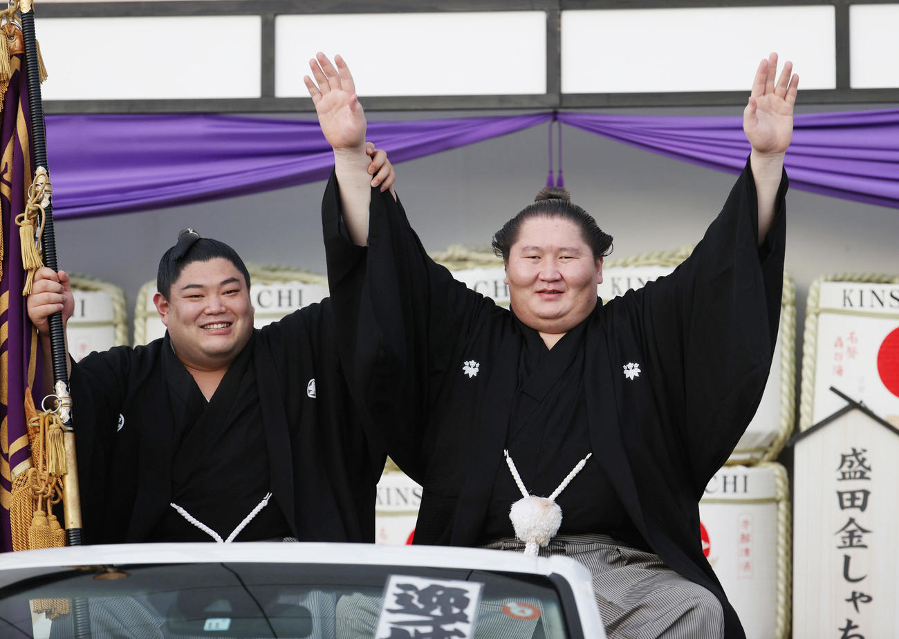2022年7月24日、優勝パレード用の車に乗り込み、記念撮影で万歳する逸ノ城（右）。旗手は阿炎