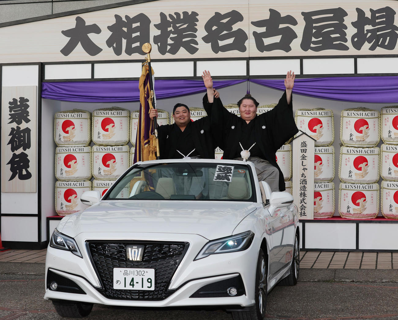 2022年7月24日、優勝パレード用の車に乗り込み、記念撮影でバンザイする逸ノ城（右）。旗手は阿炎