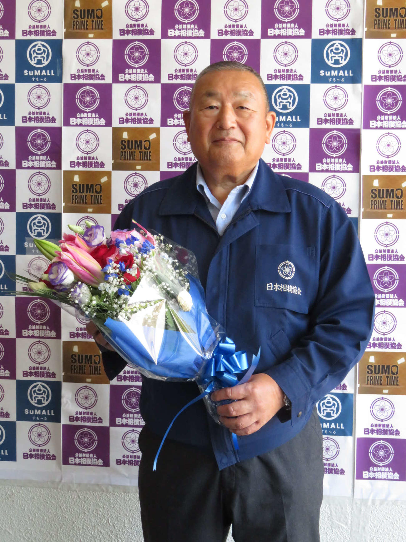 4月に定年を迎え、報道陣から贈られた花束を手にする入間川親方