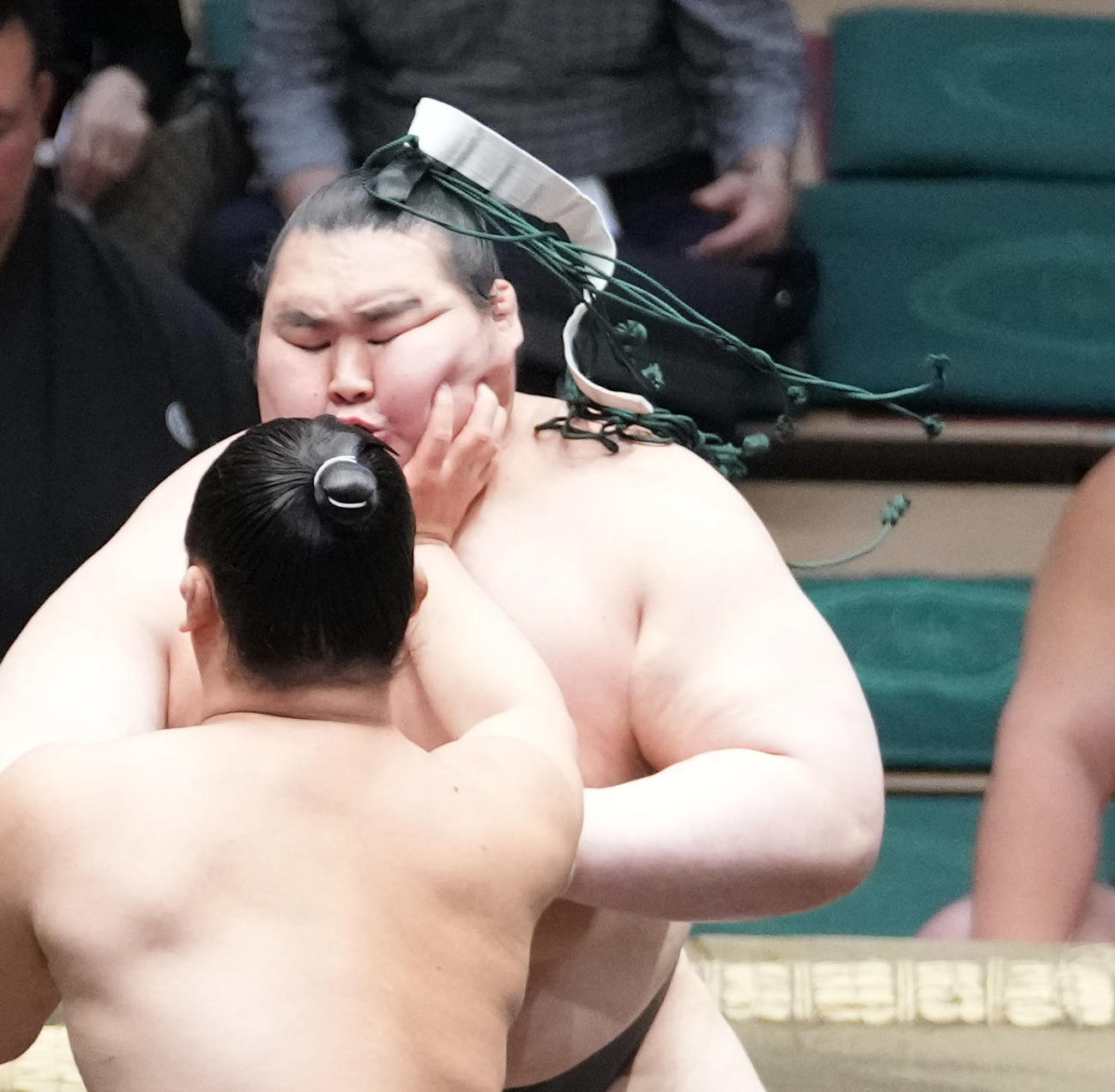栃丸（右奥）はまわしに着用していた下がりが外れまげに絡まった状態で取組を続ける（撮影・小沢裕）