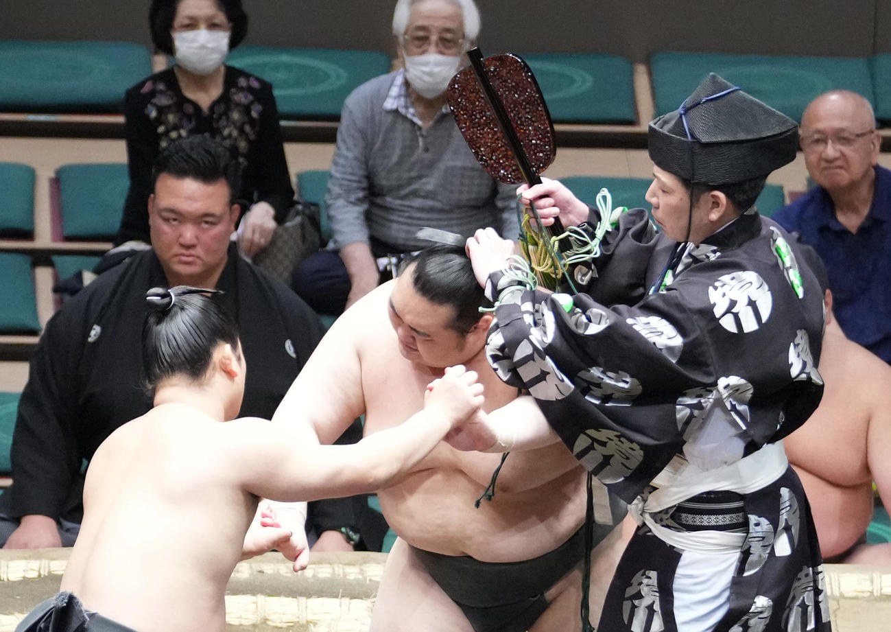 行司の木村千鷲（右）は両者に「待った」を掛け取組中栃丸（中央）のまげに絡まった下がりを解く（撮影・小沢裕）
