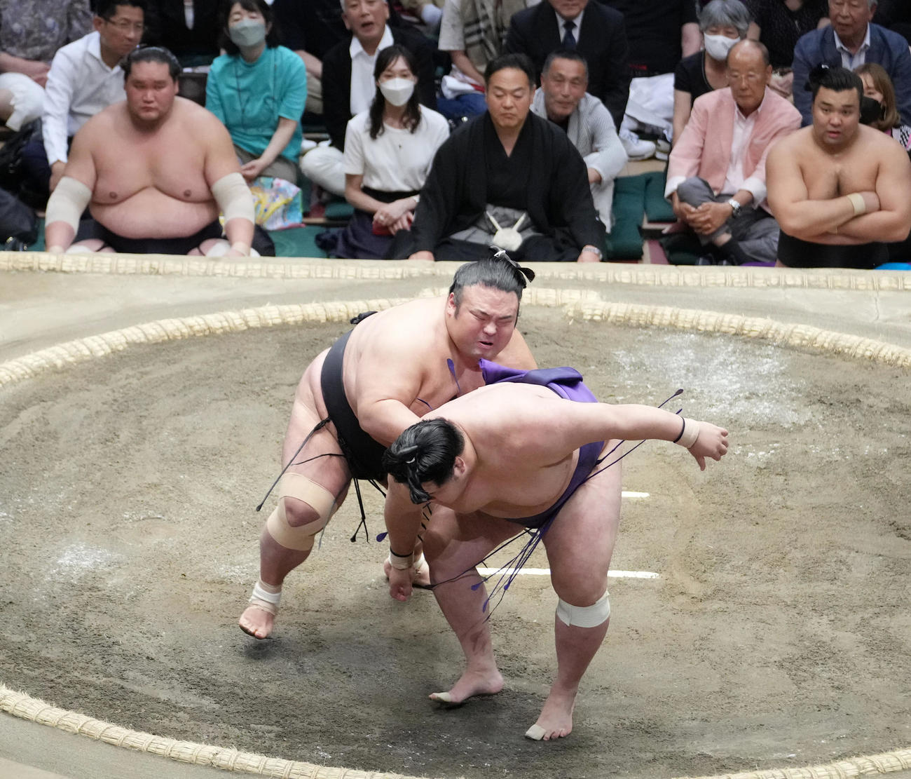 貴景勝は送り出しで明生（手前）を破る。左奥から土俵下控えの照ノ富士、霧馬山（撮影・小沢裕）