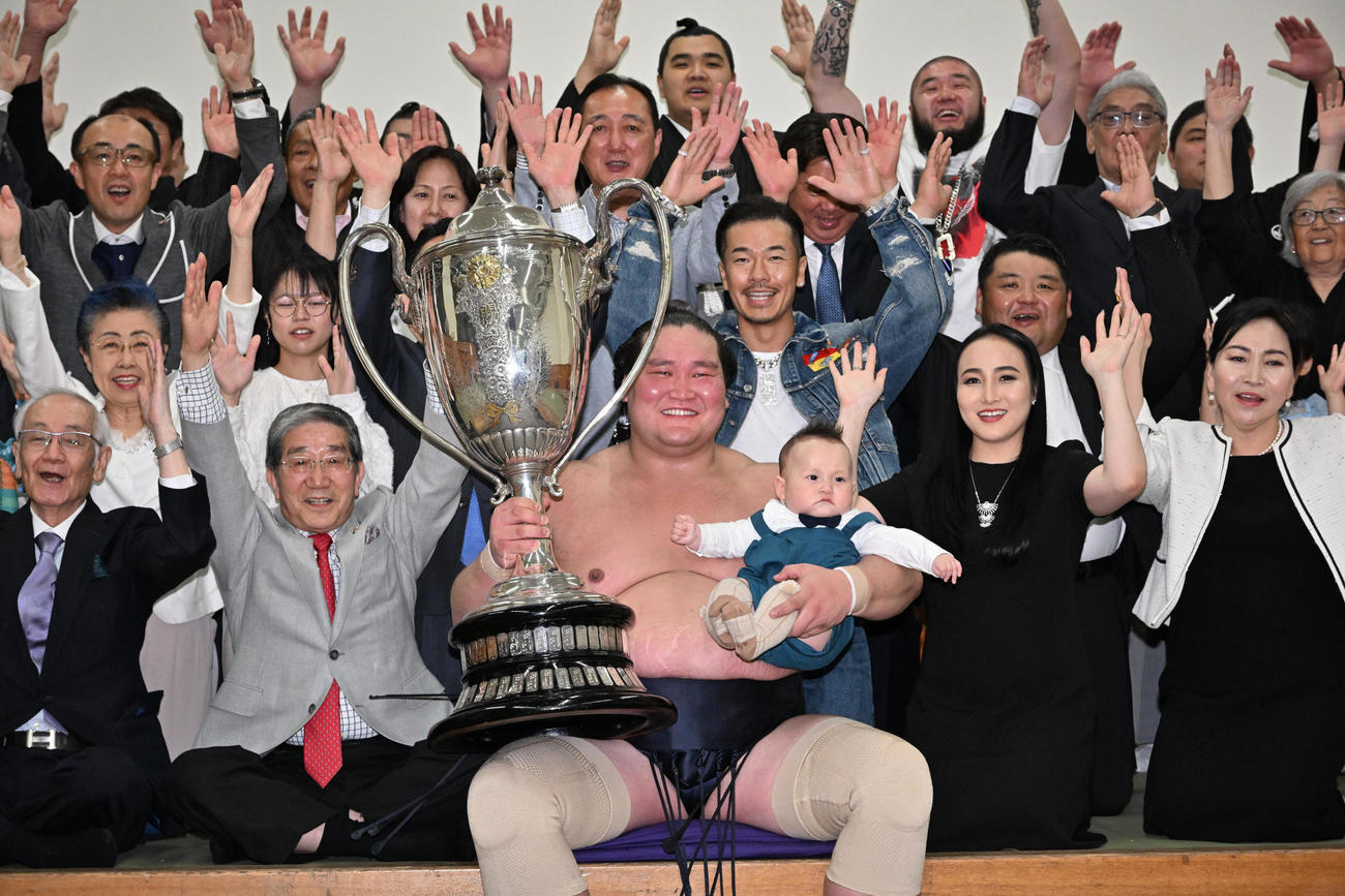 夏場所千秋楽　優勝し、賜杯を手に愛息のテムジン君を抱いて笑顔を見せる横綱照ノ富士（2023年5月28日撮影）