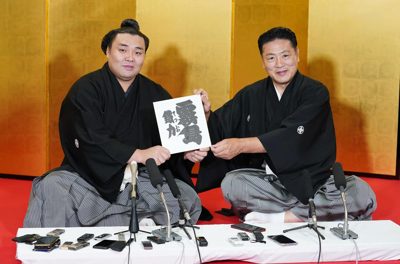 大関昇進伝達式後の記者会見で師匠のしこ名「霧島」への改名を発表し色紙を持つ霧馬山（左）と陸奥親方（撮影・小沢裕）