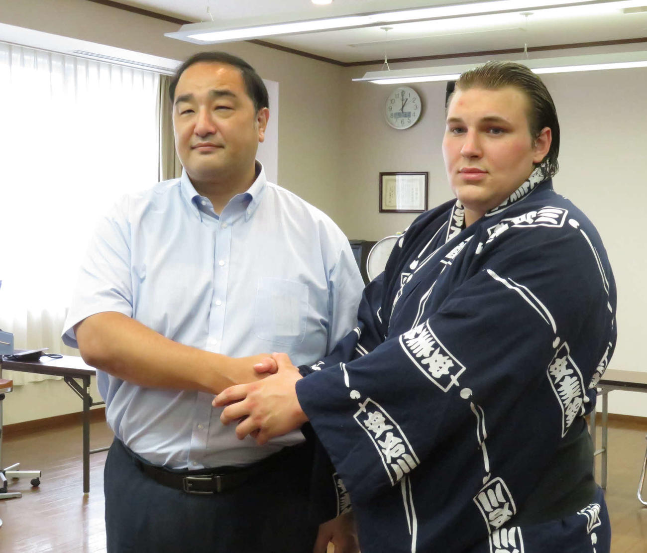 新弟子検査を受検したウクライナ出身のヤブグシシン・ダニーロ（右）は、師匠の安治川親方と握手