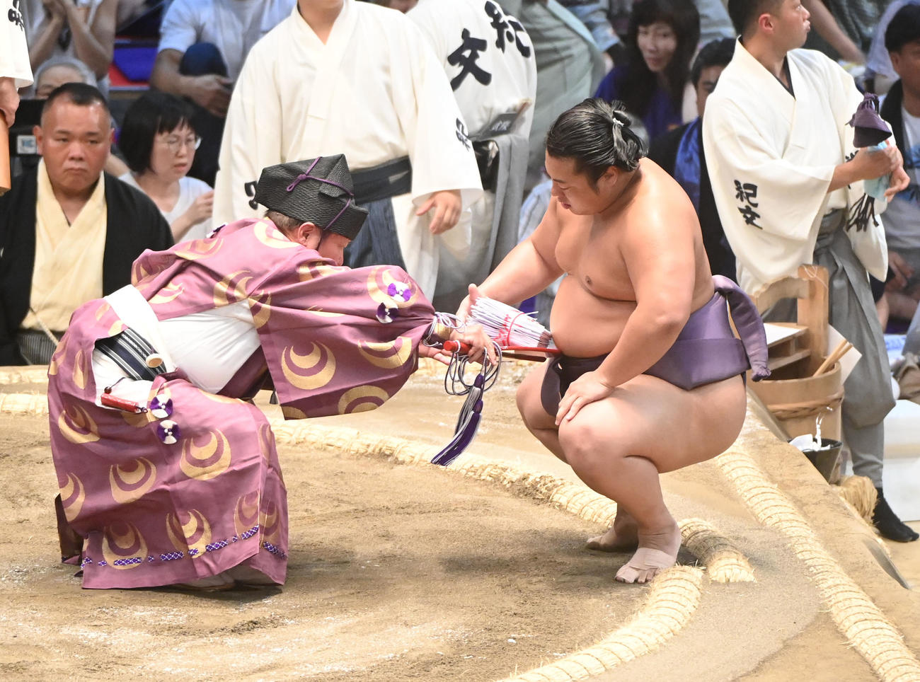 照ノ富士を破り懸賞を受け取る翔猿の手からこぼれるも式守伊之助が落ちないように支える（撮影・森本幸一）