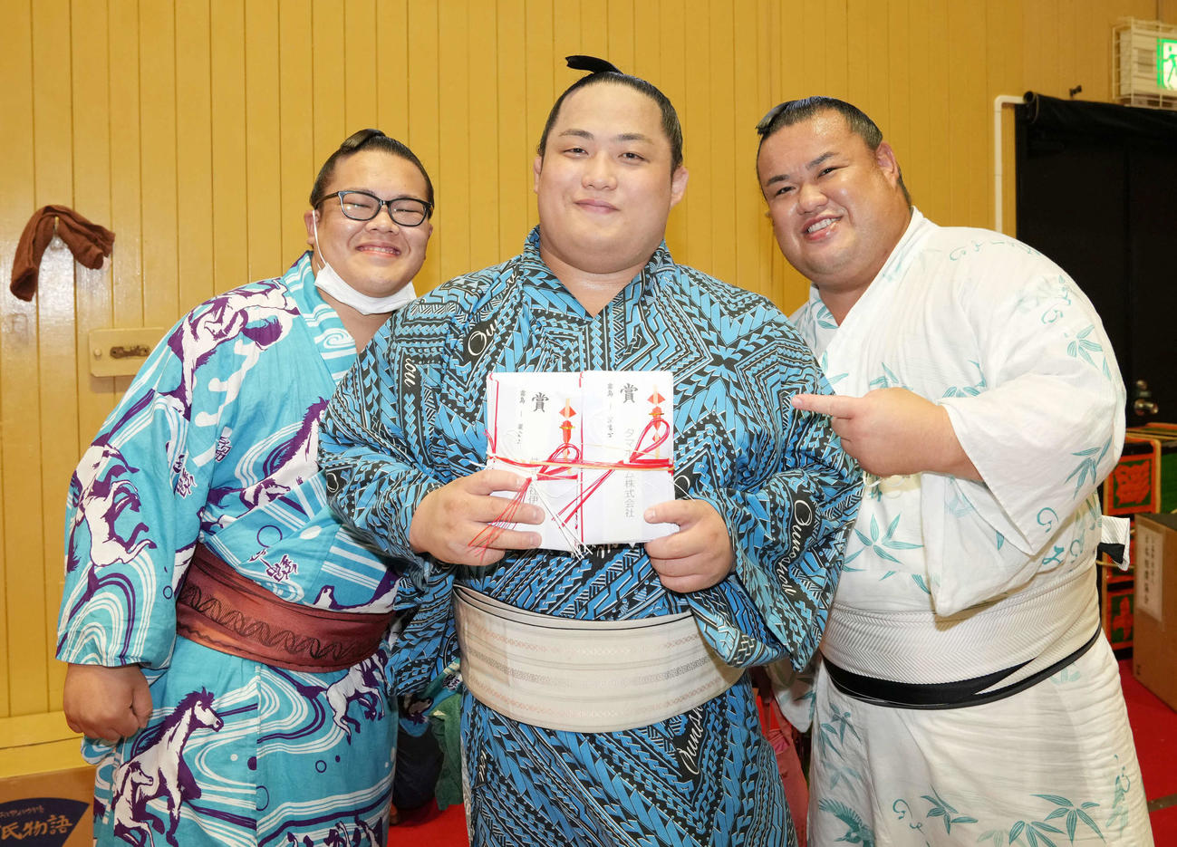 結びの一番で霧島から銀星を挙げた翠富士（中央）は懸賞金の束を手に付け人らと笑顔を見せる（撮影・小沢裕）