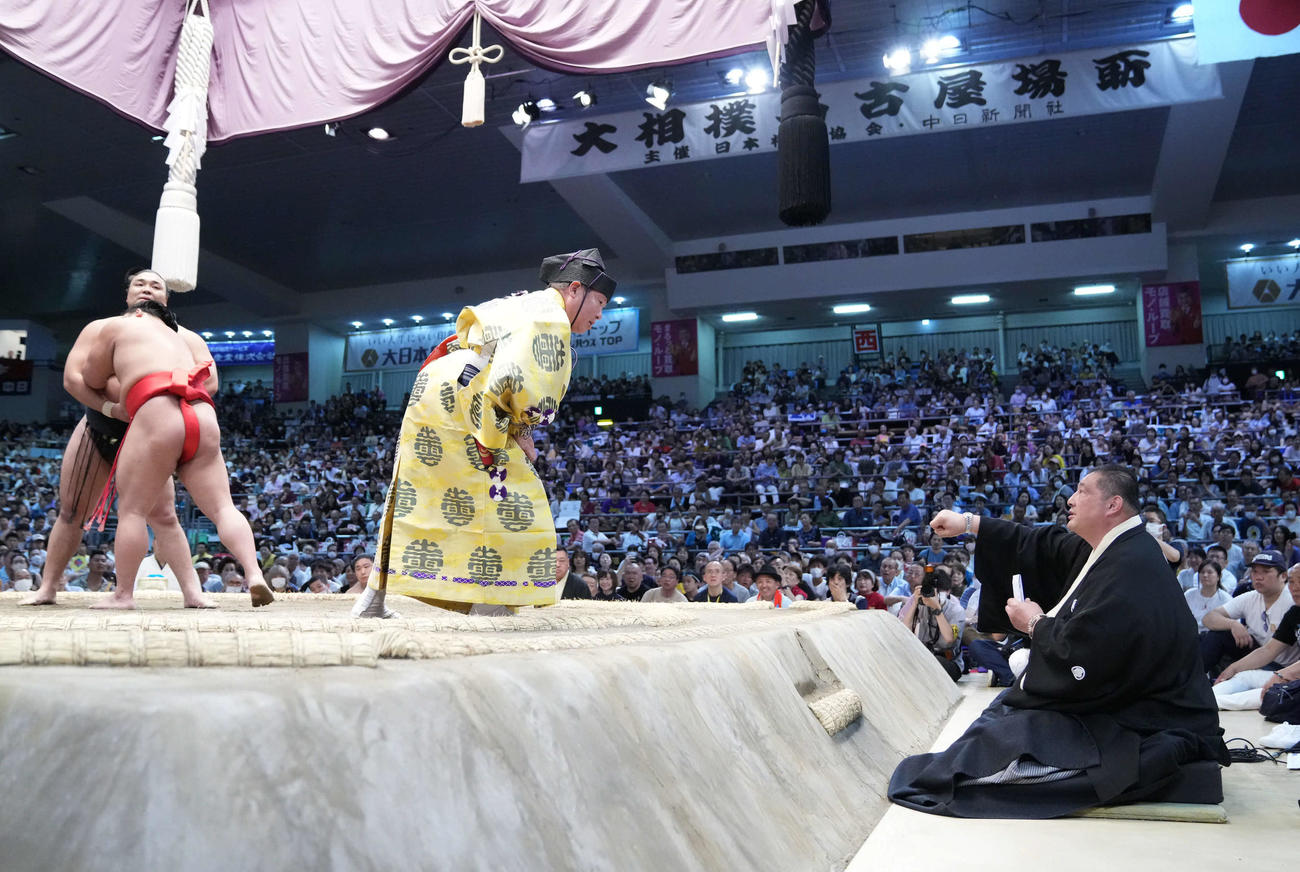 行司の式守伊之助（中央）は佐渡ケ嶽審判長（右）からまわしが締まったかどうか確認するよう注文を受ける（撮影・小沢裕）