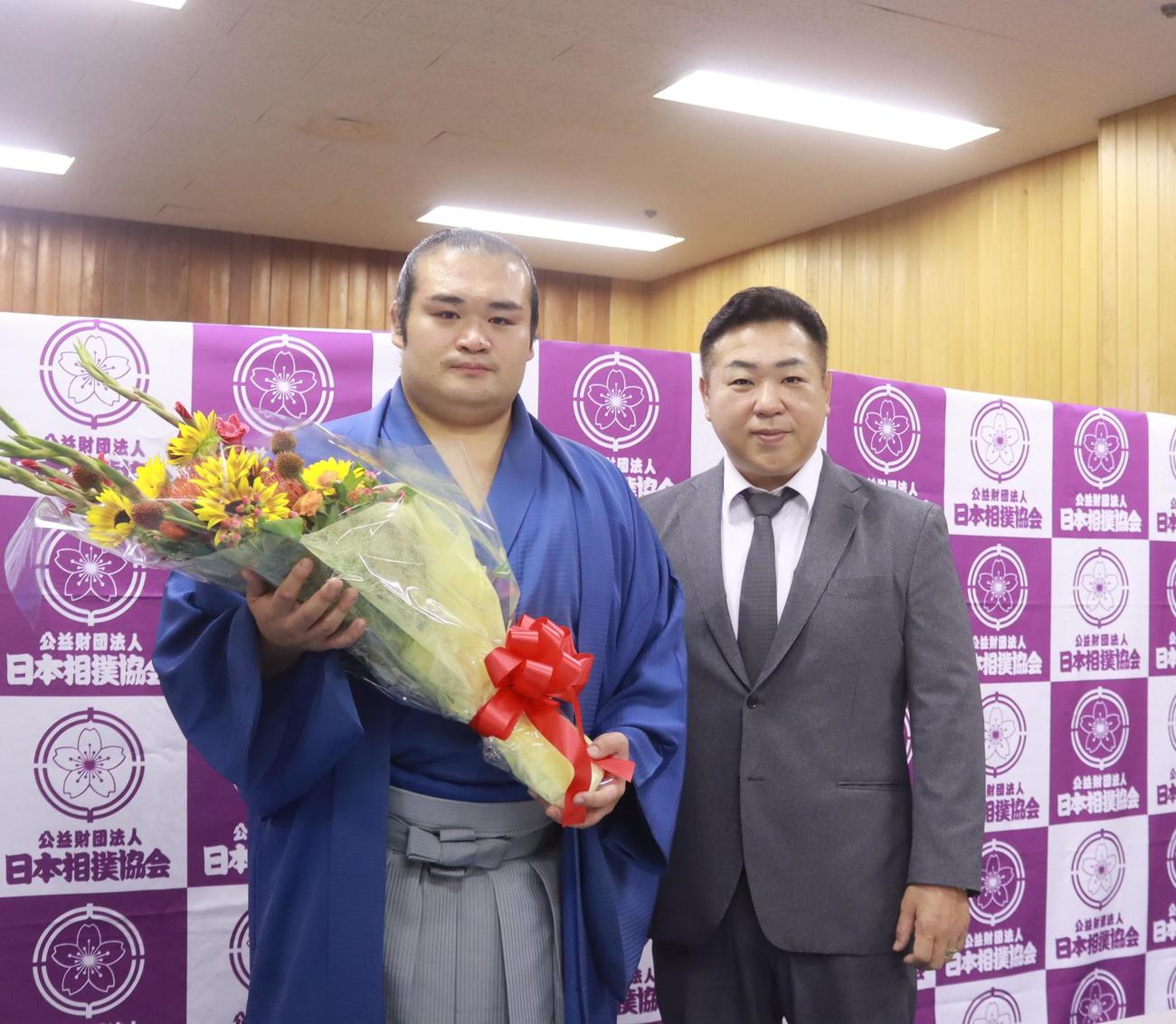 現役引退を発表した千代の国（左）は贈られた花束を手に、師匠の九重親方と写真に納まる（日本相撲協会提供）