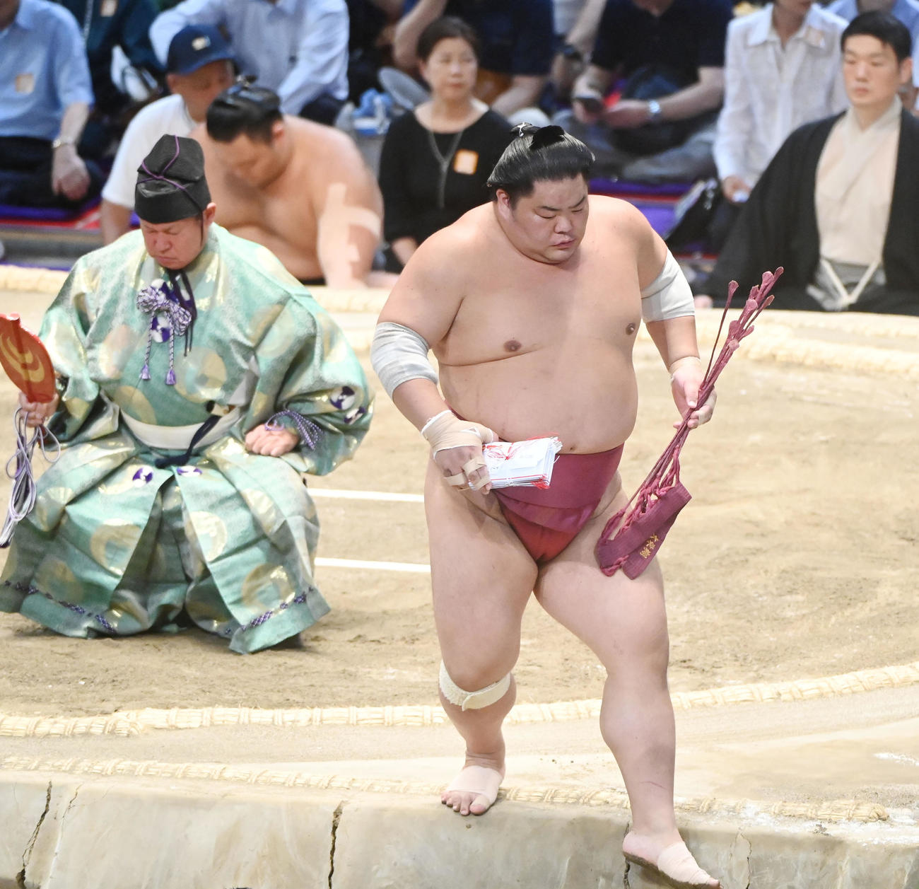 阿武咲をはたき込みで破り懸賞を手に土俵を降りる大栄翔（撮影・森本幸一）