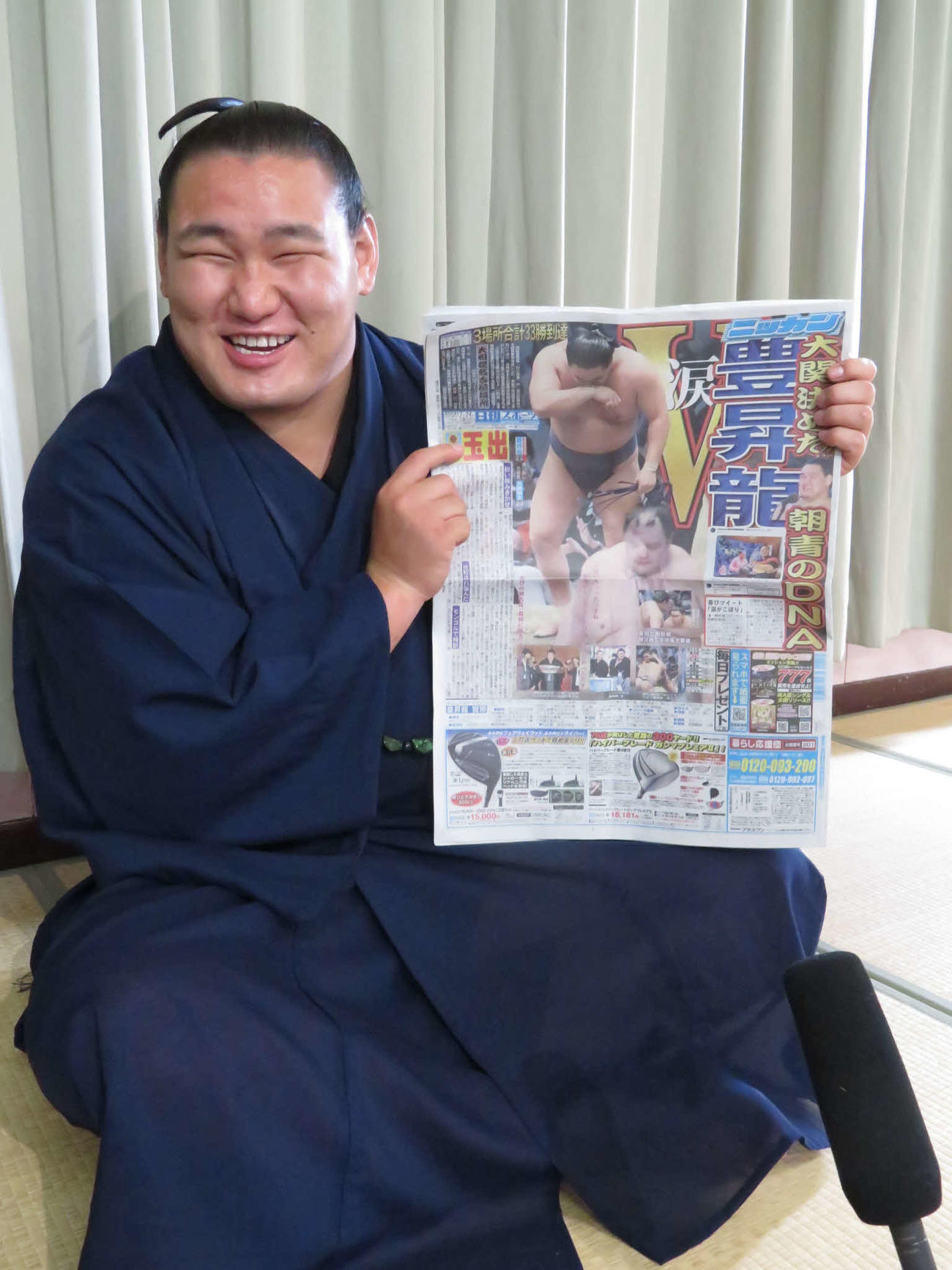 一夜明け会見後、24日付の本紙を手に満面の笑みを見せる豊昇龍