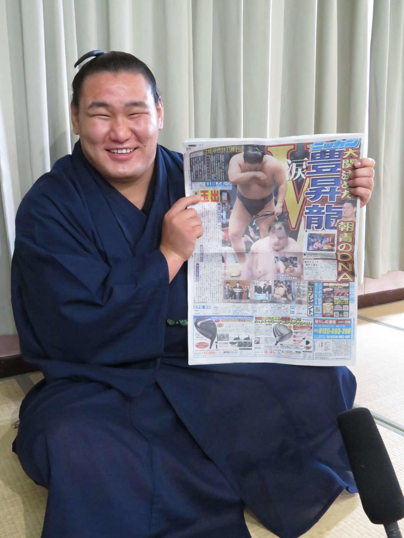 一夜明け会見後、24日付の本紙を手に満面の笑みを見せる豊昇龍