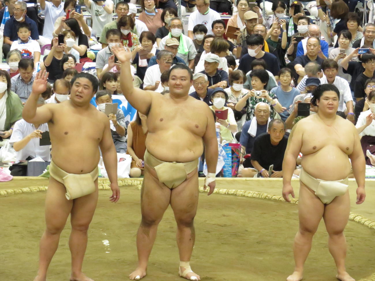 質問コーナーで、集まった地元ファンの歓声に手を振って応える朝乃山（中央）。左は若元春、右は宇良