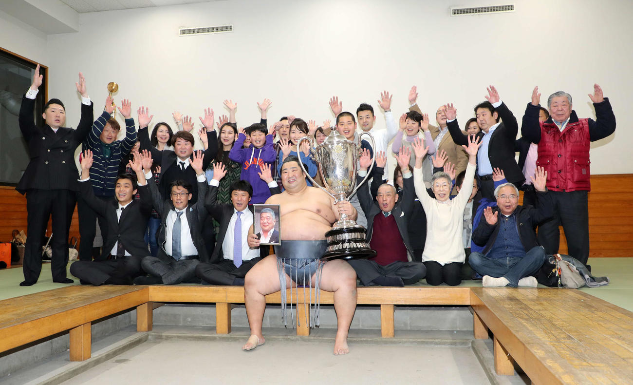 近大相撲部伊東勝人監督の遺影を手にバンザイする徳勝龍（中央）。後列中央は千恵夫人（撮影・鈴木正人）