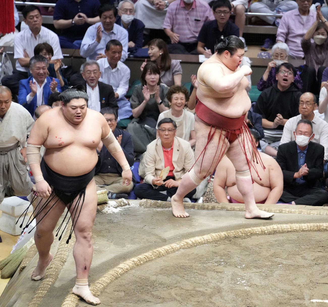 阿炎（左）を寄り切りで破った熱海富士は流血した鼻を押さえる（撮影・小沢裕）