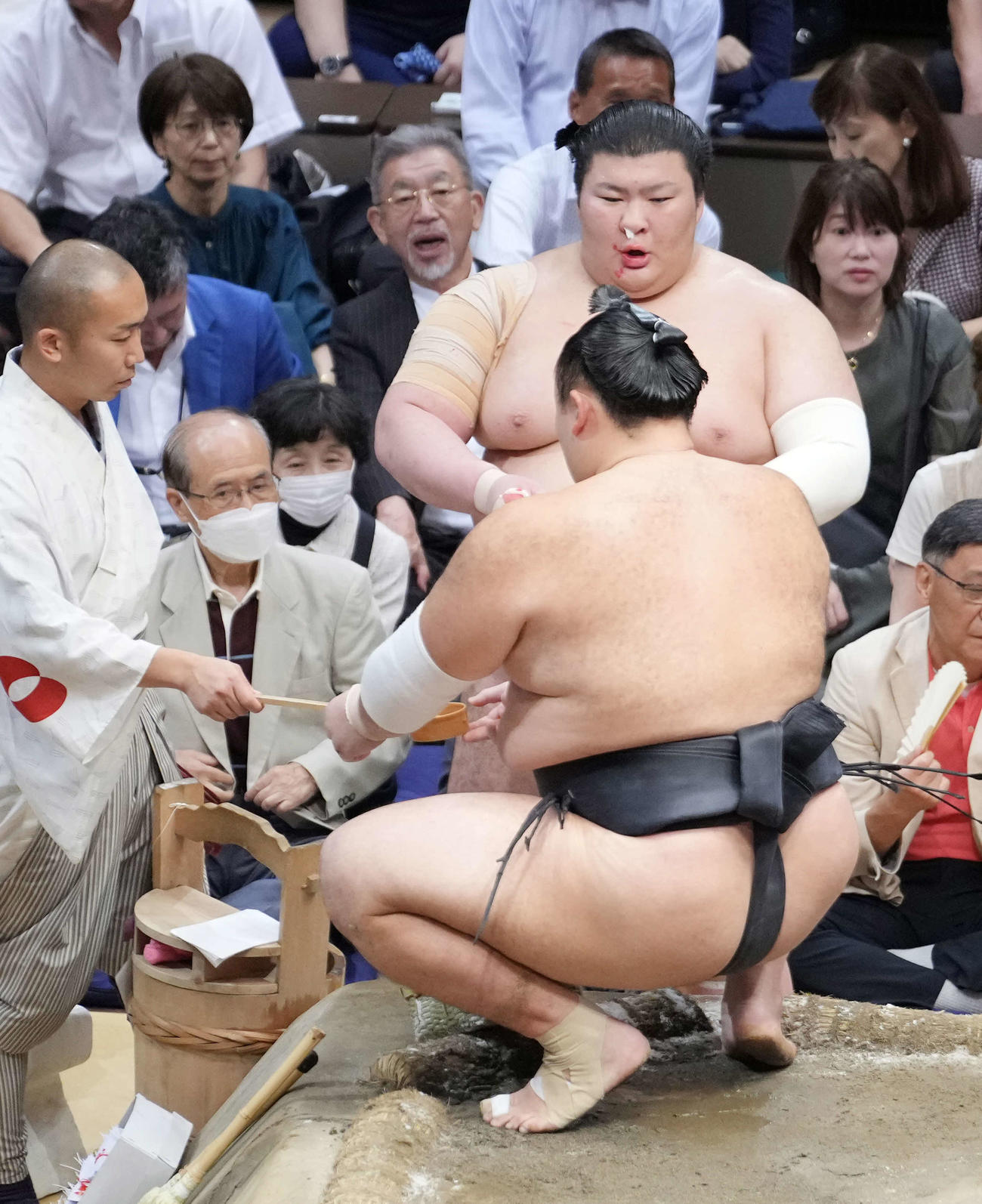 3敗を死守した熱海富士は鼻血止めのティッシュをしながら朝乃山（手前）に水を付ける（撮影・小沢裕）