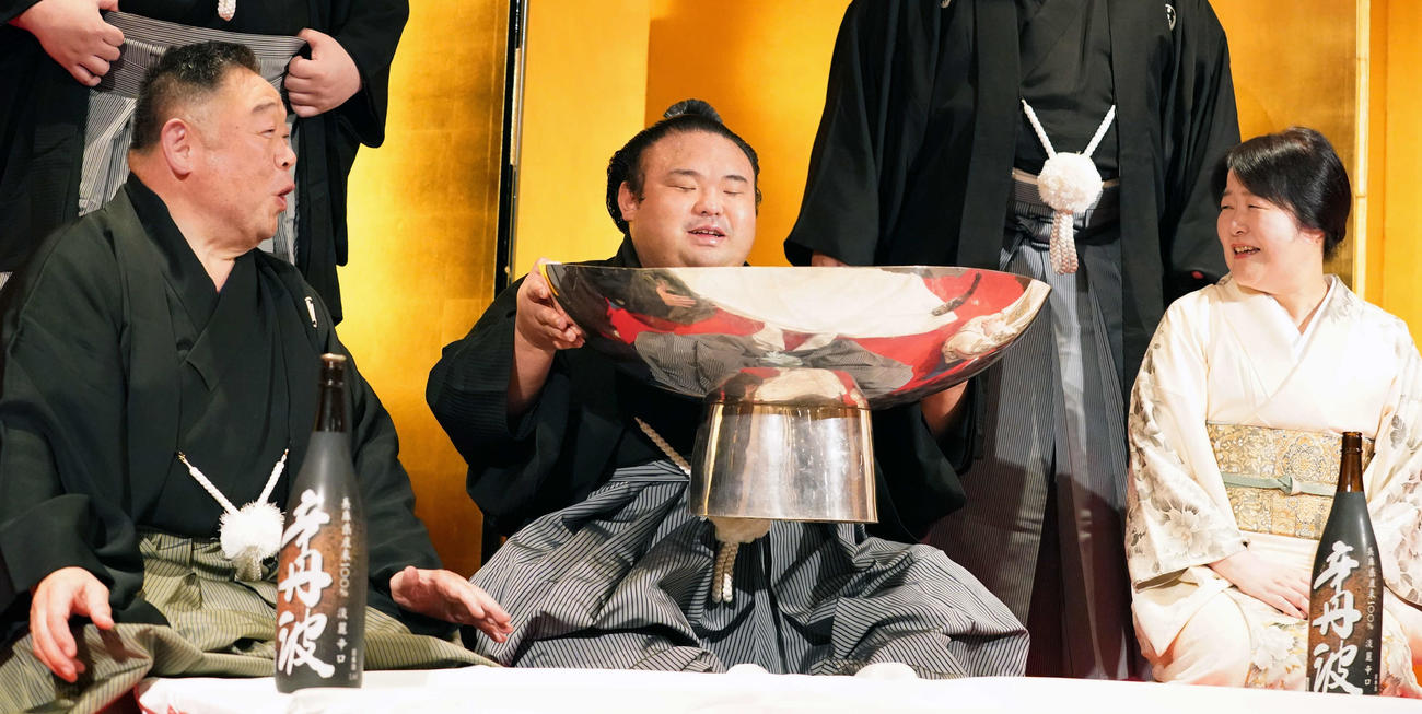 優勝した貴景勝（中央）は常盤山親方（左）、おかみの留美子さんから銀杯に注がれたお酒を飲み笑顔を見せる（撮影・小沢裕）