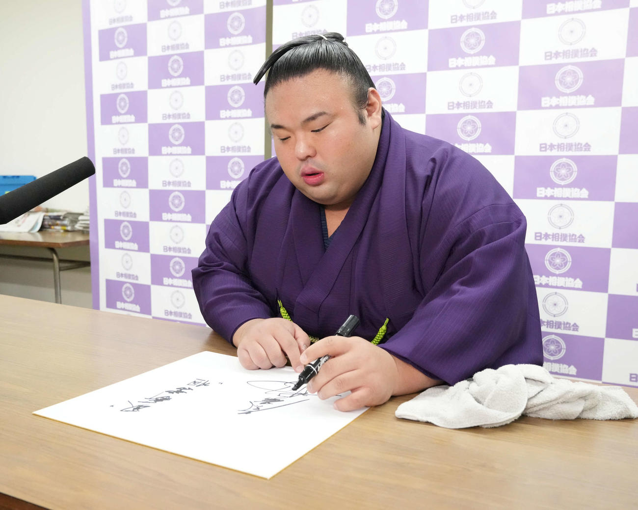 優勝一夜明け会見に臨んだ貴景勝は報道陣から手渡された色紙に自身の好きな言葉をしたためる（撮影・小沢裕）