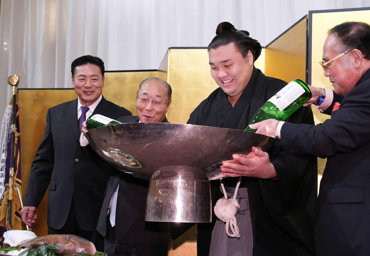 千秋楽パーティーで後援会関係者から大杯にお酒をそそがれ笑顔を見せる霧島。左端は師匠の陸奥親方（撮影・小沢裕）