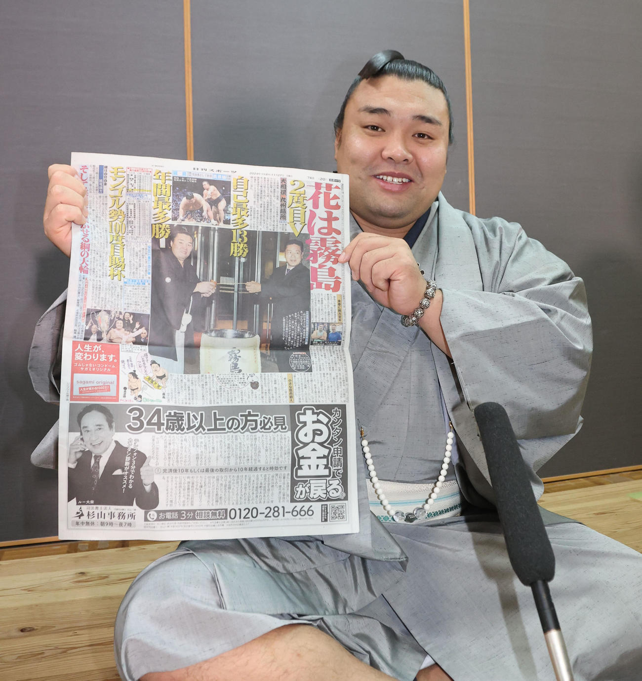 優勝から一夜明け、本紙を手に笑顔を見せる霧島（撮影・梅根麻紀）