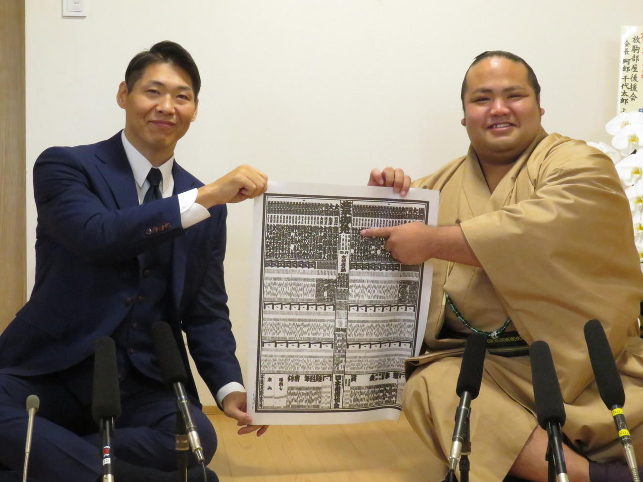 新番付を手に、自身のしこ名を指さし笑顔を見せる島津海（右）。左は放駒親方