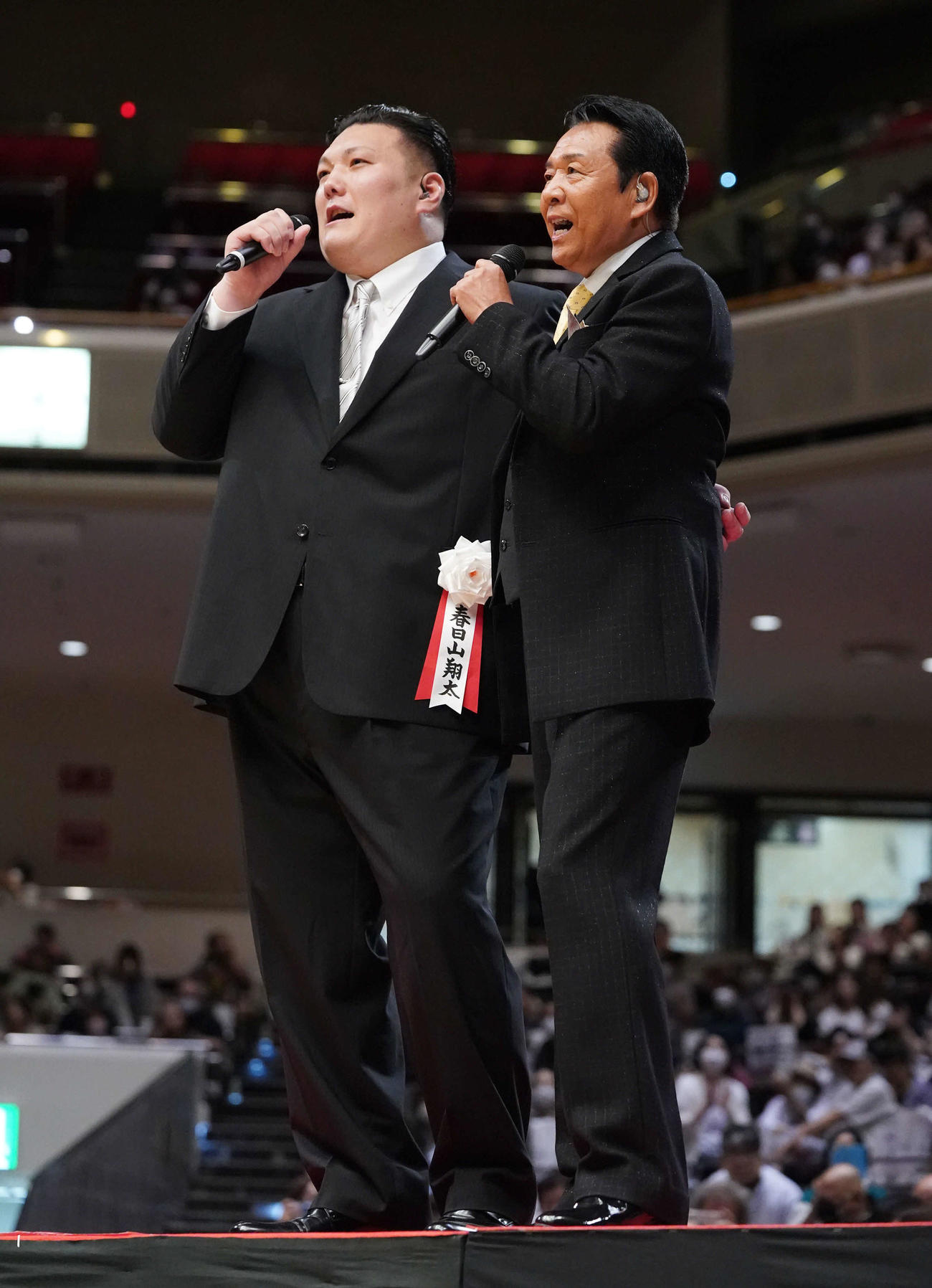 断髪式後のあいさつを終えた春日山親方（元関脇勢）はスペシャルゲストで歌手の山本譲二（右）と土俵脇に設けられたステージで熱唱する（2023年6月撮影）