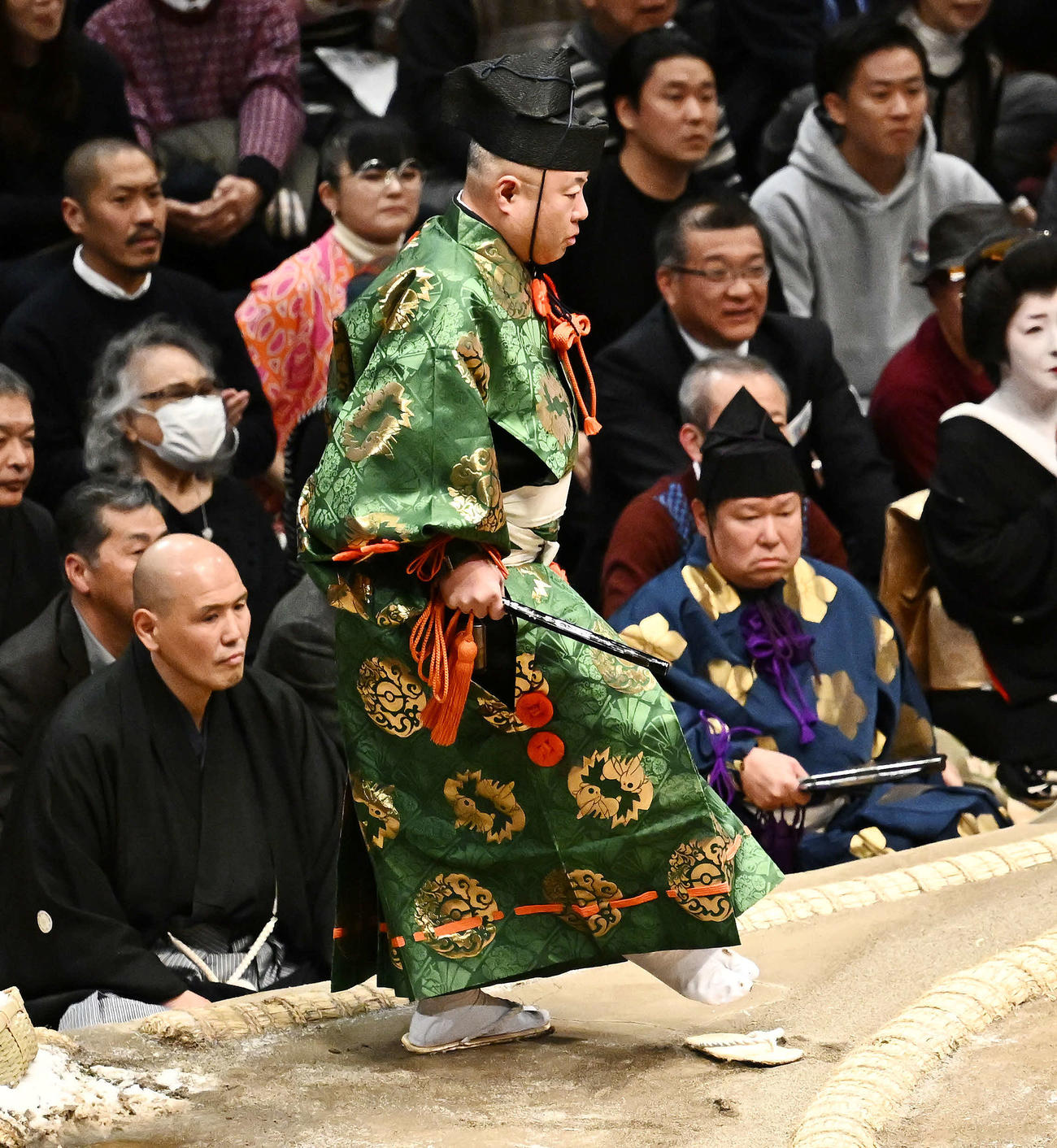 霧島と北勝富士の取り組みで転倒し、脱げた草履を履く行司木村容堂（撮影・滝沢徹郎）