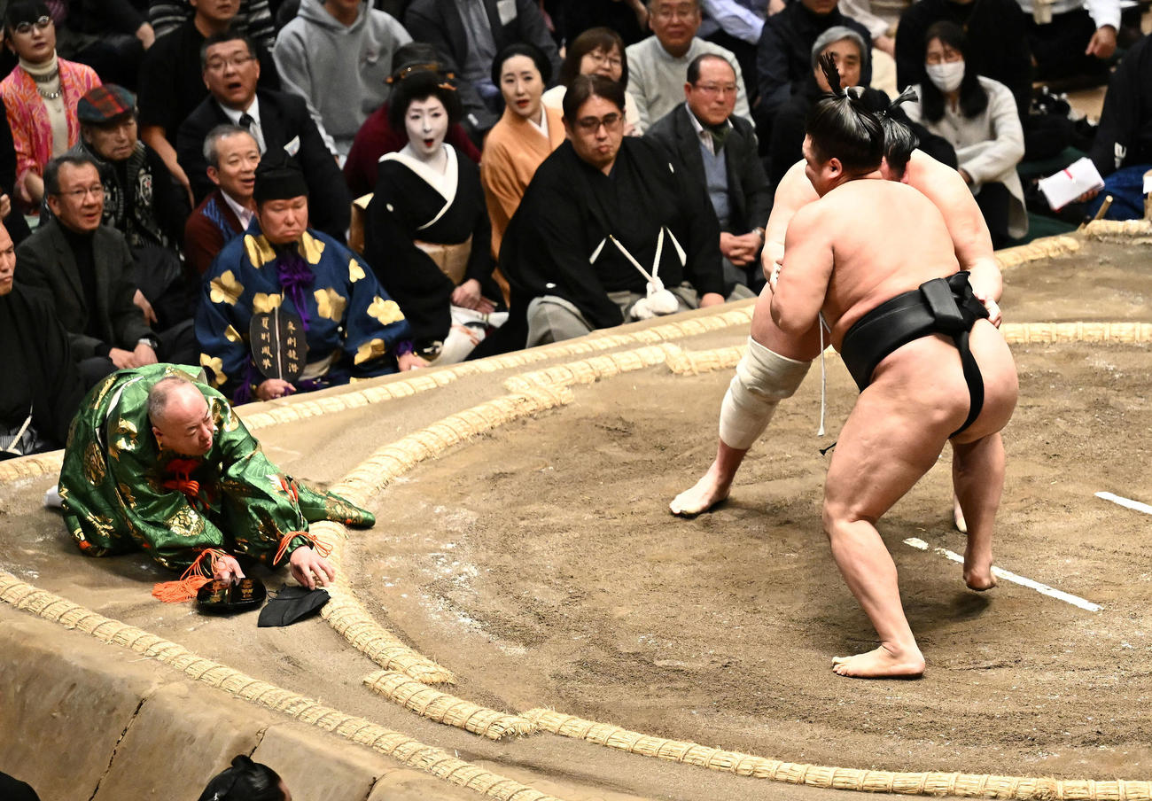 霧島と北勝富士の取り組みで転倒し、落ちた帽子に手を伸ばす行司木村容堂（左）（撮影・滝沢徹郎）