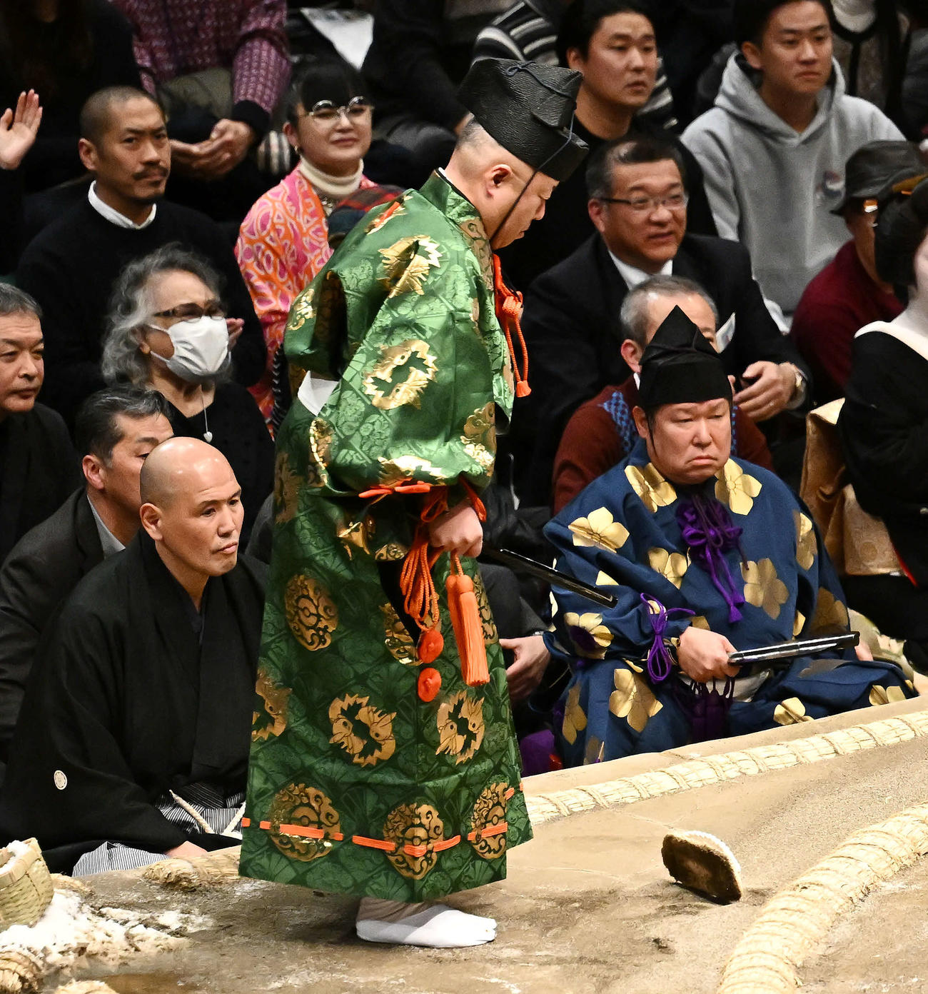 霧島と北勝富士の取り組みで転倒し、脱げた草履を履く行司木村容堂（撮影・滝沢徹郎）