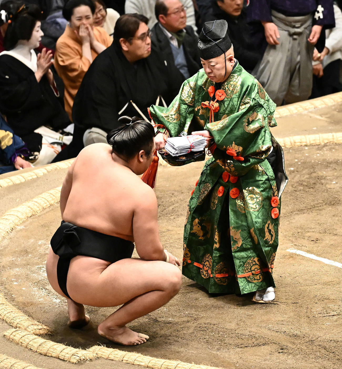 北勝富士を破った霧島（左）に懸賞を渡す行司木村容堂（撮影・滝沢徹郎）