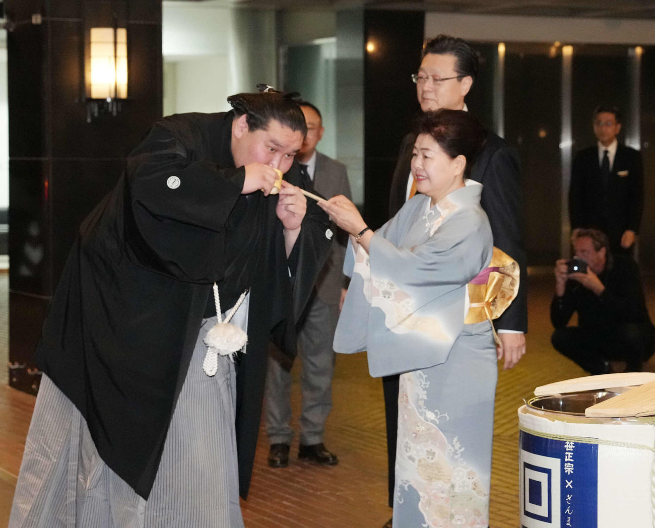 打ち上げパーティー会場のホテル前でおかみの淳子さんから水付けを受ける照ノ富士（左）。後方右は師匠の伊勢ケ浜親方（撮影・小沢裕）