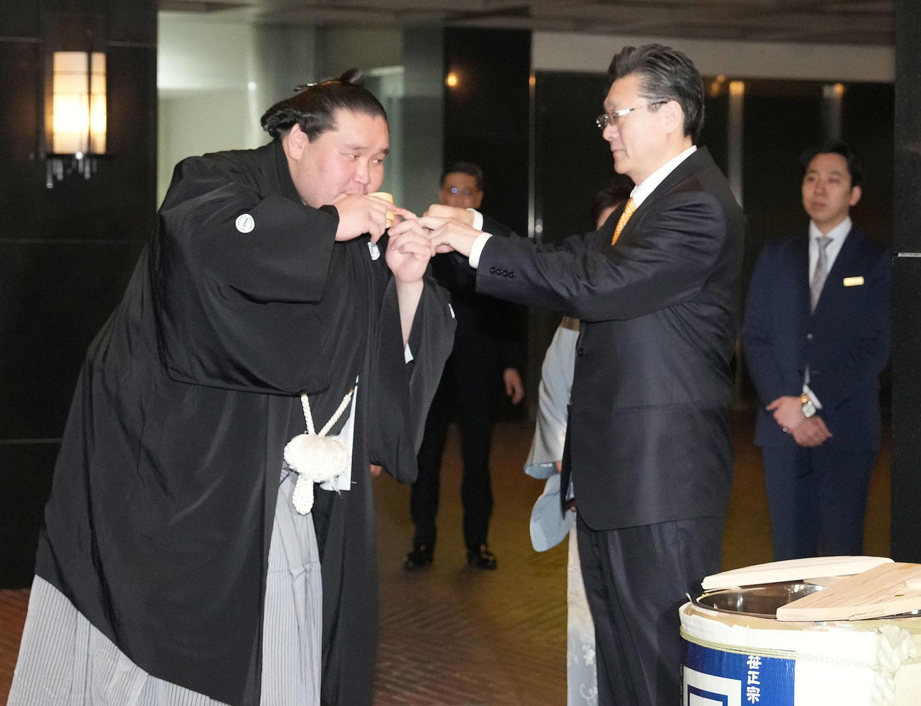 打ち上げパーティー会場のホテル前で師匠の伊勢ケ浜親方（右）から水付けを受ける照ノ富士（撮影・小沢裕）