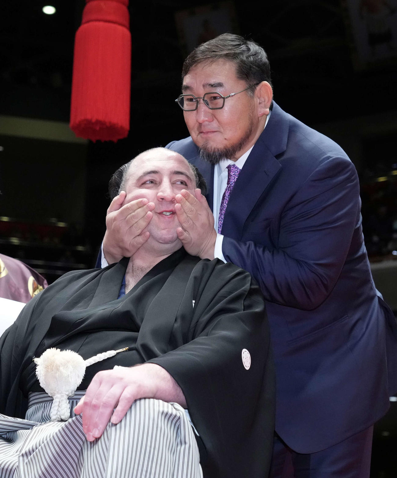 はさみを入れた元横綱の朝青龍明徳氏（右）から両手で抱き寄せられる栃ノ心（撮影・小沢裕）