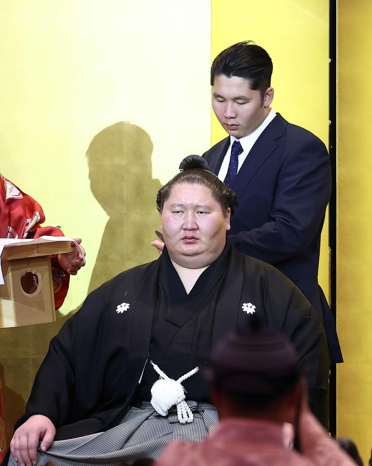 弟のムンクドルジさんにはさみを入れてもらう逸ノ城（撮影・河田真司）