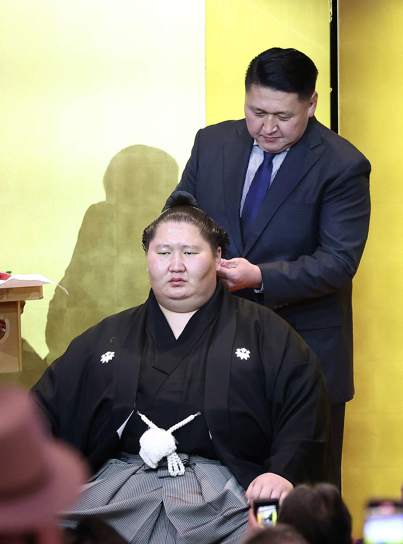 大島親方（奥）にはさみを入れてもらう逸ノ城（撮影・河田真司）