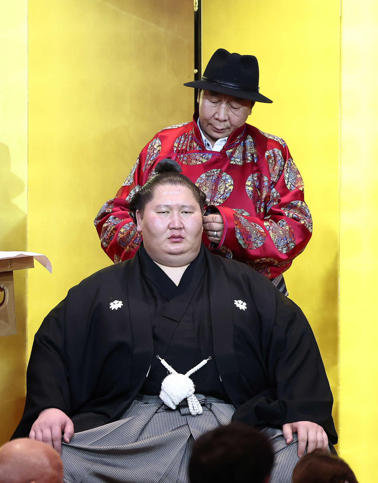 父のアルタン・ホーヤグーさん（奥）にはさみを入れてもらう逸ノ城（撮影・河田真司）