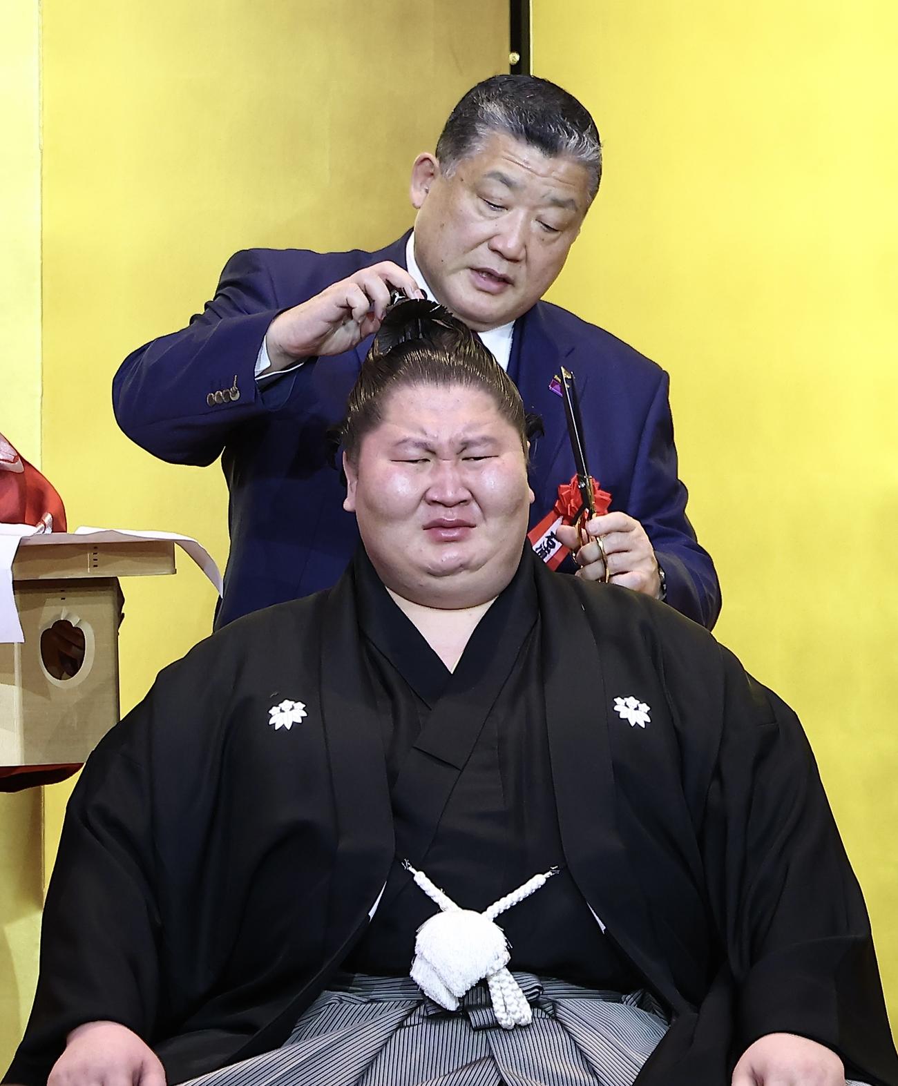 鳥取城北・石浦相撲部総監督（後方）に止めばさみを入れてもらう逸ノ城（撮影・河田真司）
